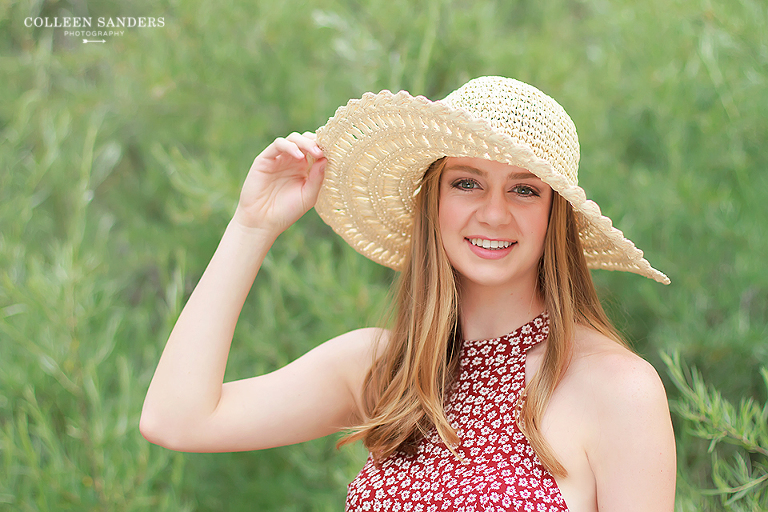 Classic high school senior portraits with one of her senior models by the lake with natural greenery and a hat by senior photographer Colleen Sanders near El Dorado Hills, California.