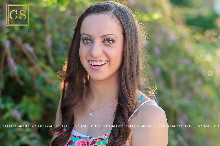 Nicole laughing during her senior portraits with golden light and flowers behind her by El Dorado Hills senior photographer Colleen Sanders.